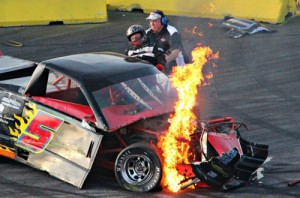 Track General Manager John Close helps to pull Ronnie Wehunt from his damaged and burning race truck after a hard crash on the frontstretch at Gresham Motorsports Park Saturday night.  Wehunt was uninjured in the crash.  Photo by Lori Sandefur Wallace