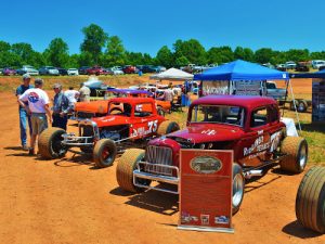 A recently restored race car driven by Georgia Racing Hall of Famer Charlie Burkhalter (right) and a replica Burkhalter racer (left) sit in the fourth turn of the Banks County Speedway during Saturday's reunion. Photo by Rob Moore